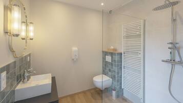 Een moderne badkamer met een wastafel, toilet, douchecabine van glas en een handdoekhouder.