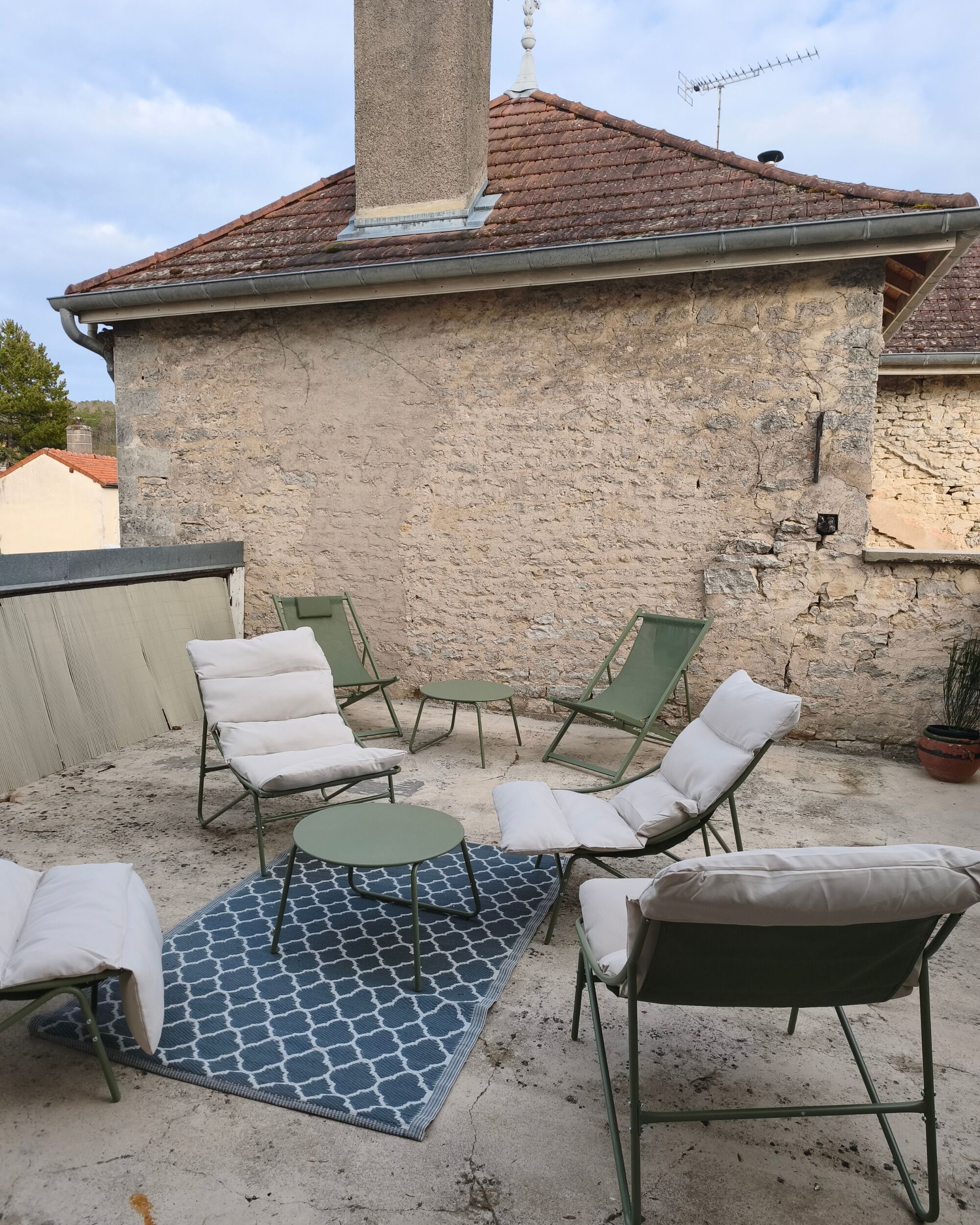 A patio with outdoor furniture, a stone wall, and a tiled roof.