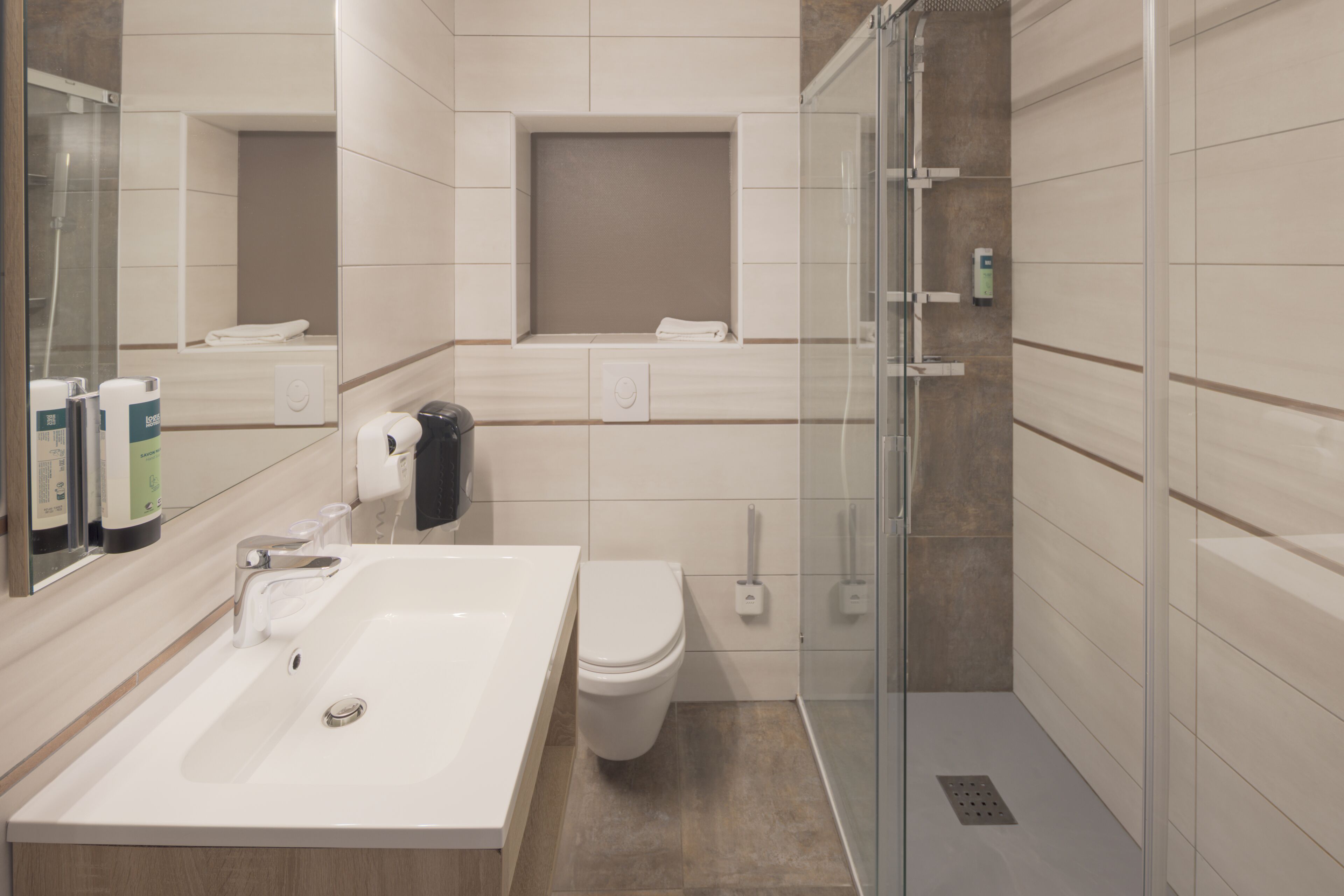 Une salle de bain moderne équipée d’un lavabo, de toilettes et d’une douche.