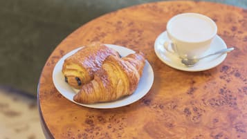 Un croissant y una taza de café sobre una mesa redonda de madera.