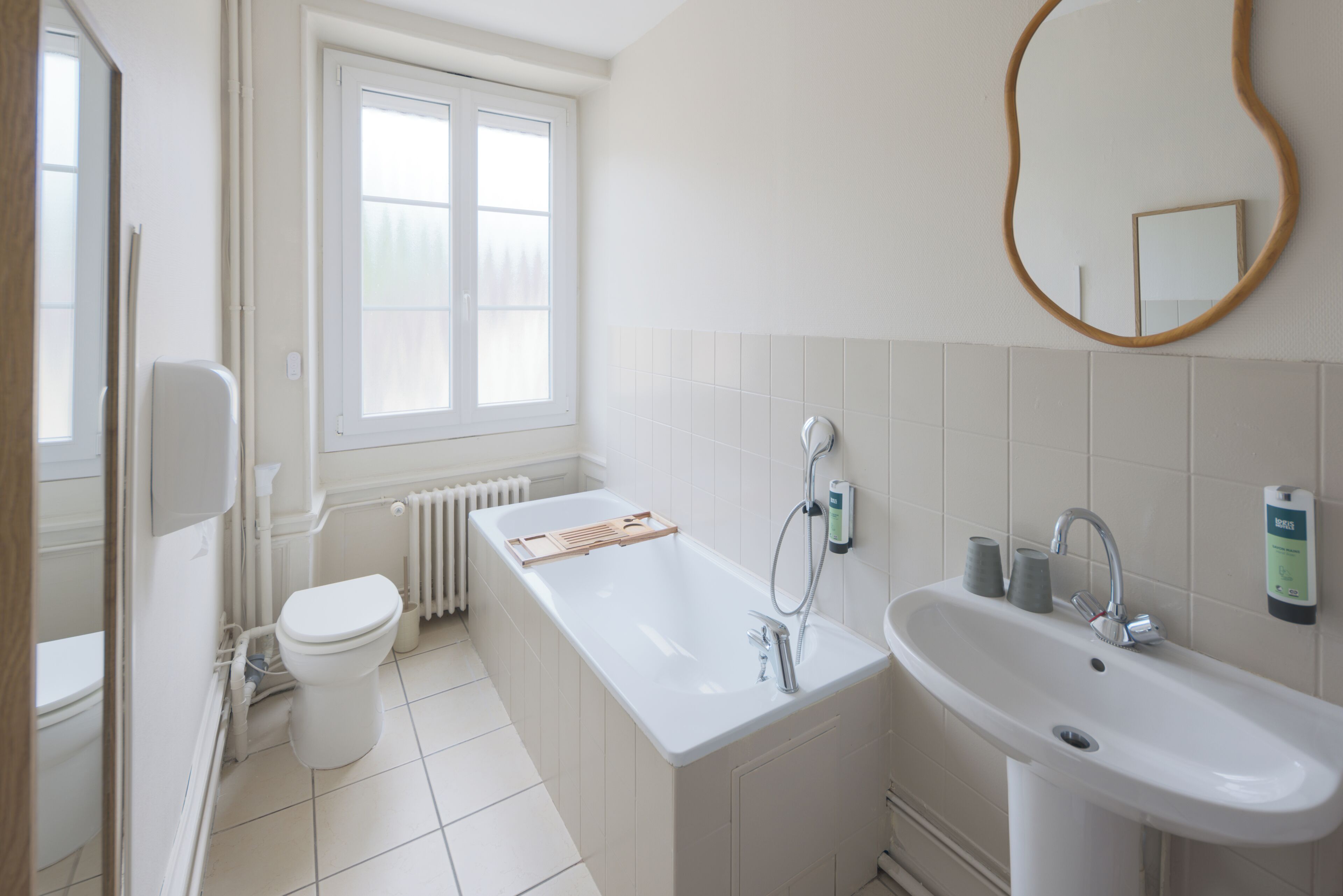 A bathroom with a toilet, a bathtub, a sink, and a window.