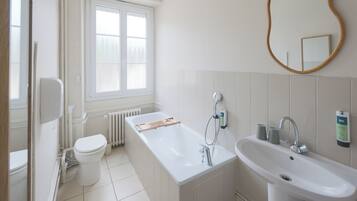 Ein Badezimmer mit Toilette, einer Badewanne, einem Waschbecken und einem Fenster.
