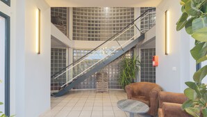 Un'ampia hall con una scalinata, un tavolo rotondo e un divano in pelle marrone.