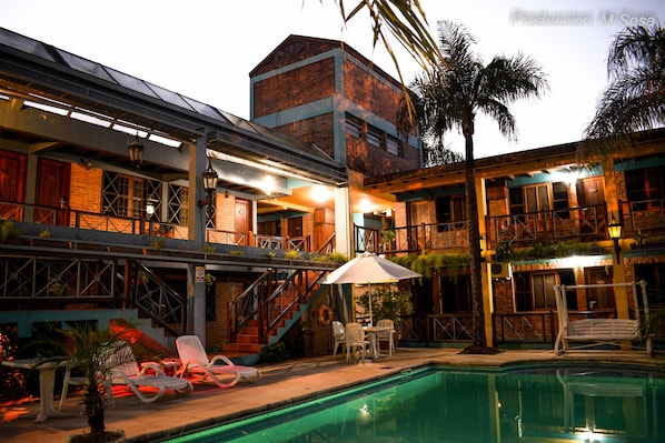 A hotel with a pool, outdoor seating, and a staircase leading to the upper floors.