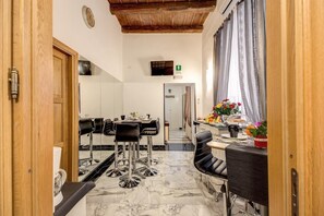 A modern kitchen with marble flooring, a dining area with black chairs, and a view of the hallway. - Il Fascino Di Roma (Rome)