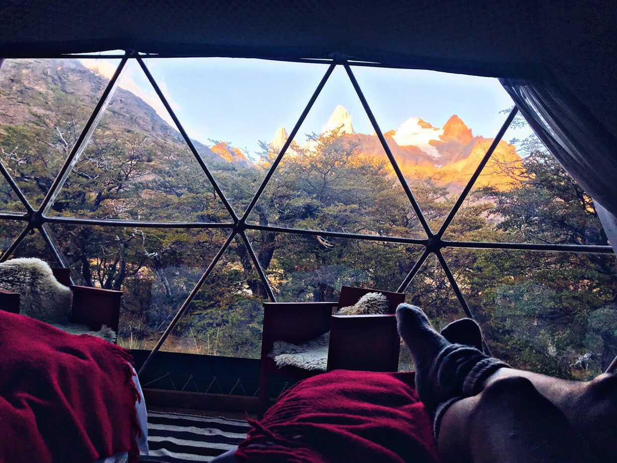 A room with a view of mountains through a geometric window structure.