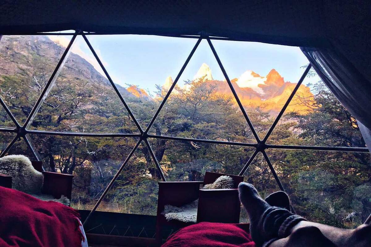 Una habitación con vistas a montañas a través de una estructura de ventana geométrica.