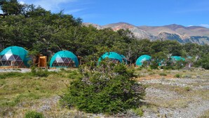 Una hilera de estructuras de cúpulas geodésicas con un paisaje natural de fondo.
