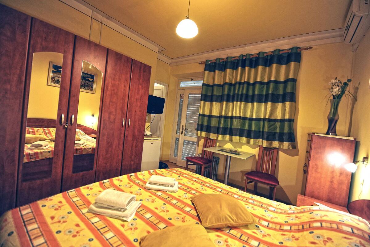 Quarto de hotel com cama, escrivaninha, cadeira e guarda-roupa.