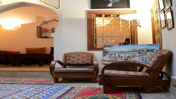 A cozy interior with a wooden chair, a cushioned bench, and a colorful rug.