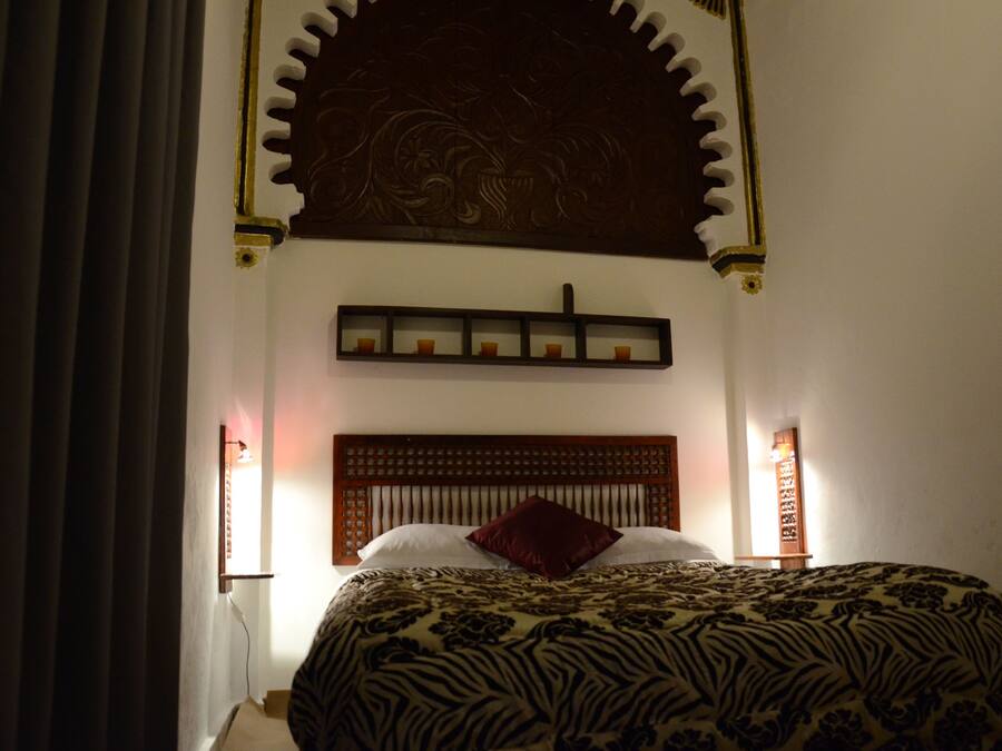A bedroom with a zebra-patterned bedspread, a wooden headboard, and a decorative wall panel above the bed.