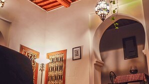 A cozy interior with a wooden ceiling, a staircase leading to an upper level, and a seating area with a table and chairs. - Dar Rehla (Tetouan)