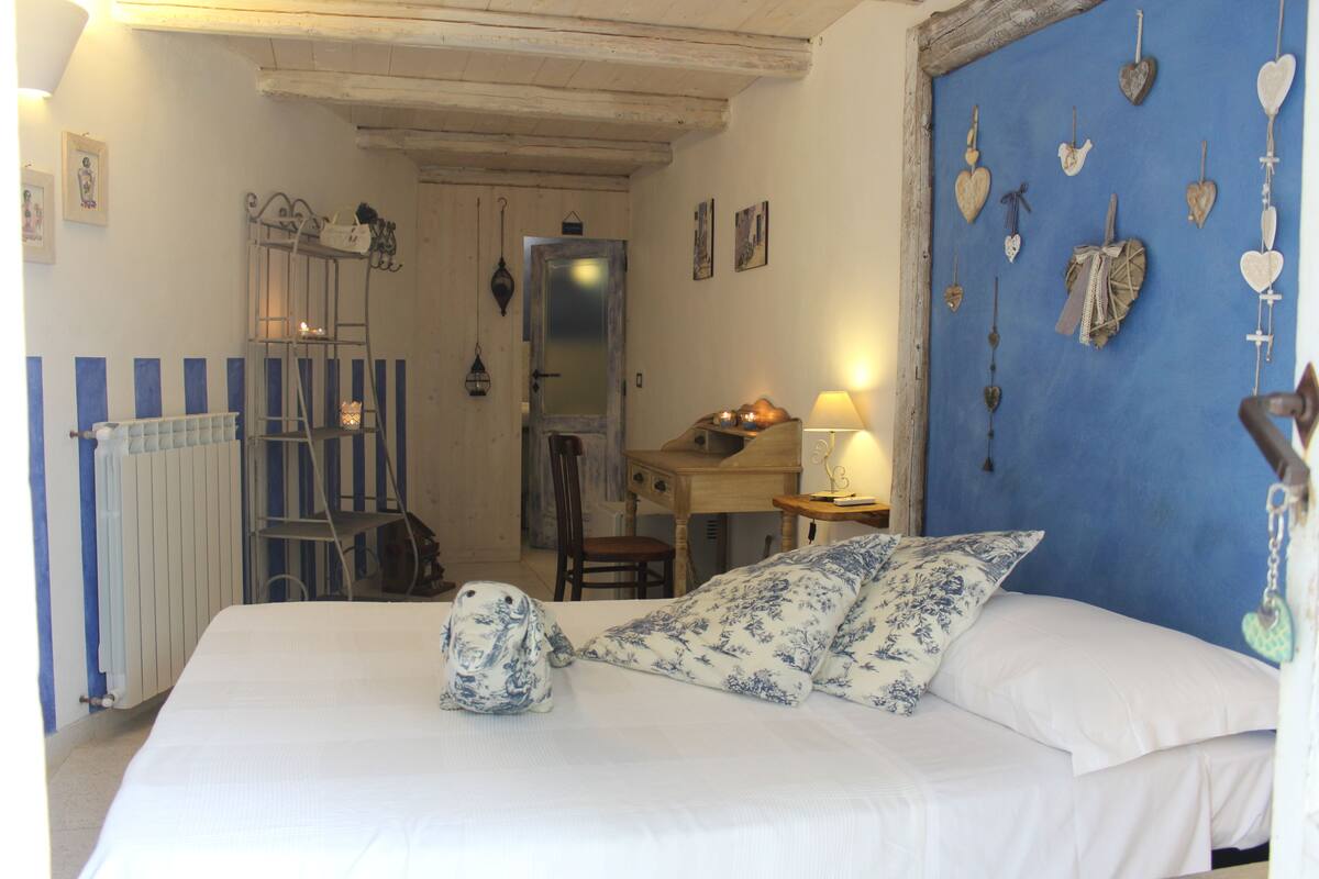 Une chambre à coucher avec un lit, un bureau et une chaise. Les murs sont décorés de motifs en forme de cœur.