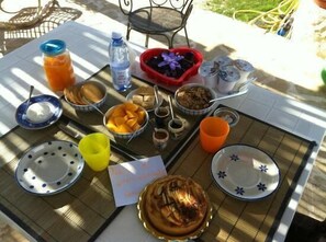 A table set with various food items and drinks, including a heart-shaped bowl of purple flowers, a bottle of water, and several bowls of fruit. - Trulli Terra Magica (Putignano)