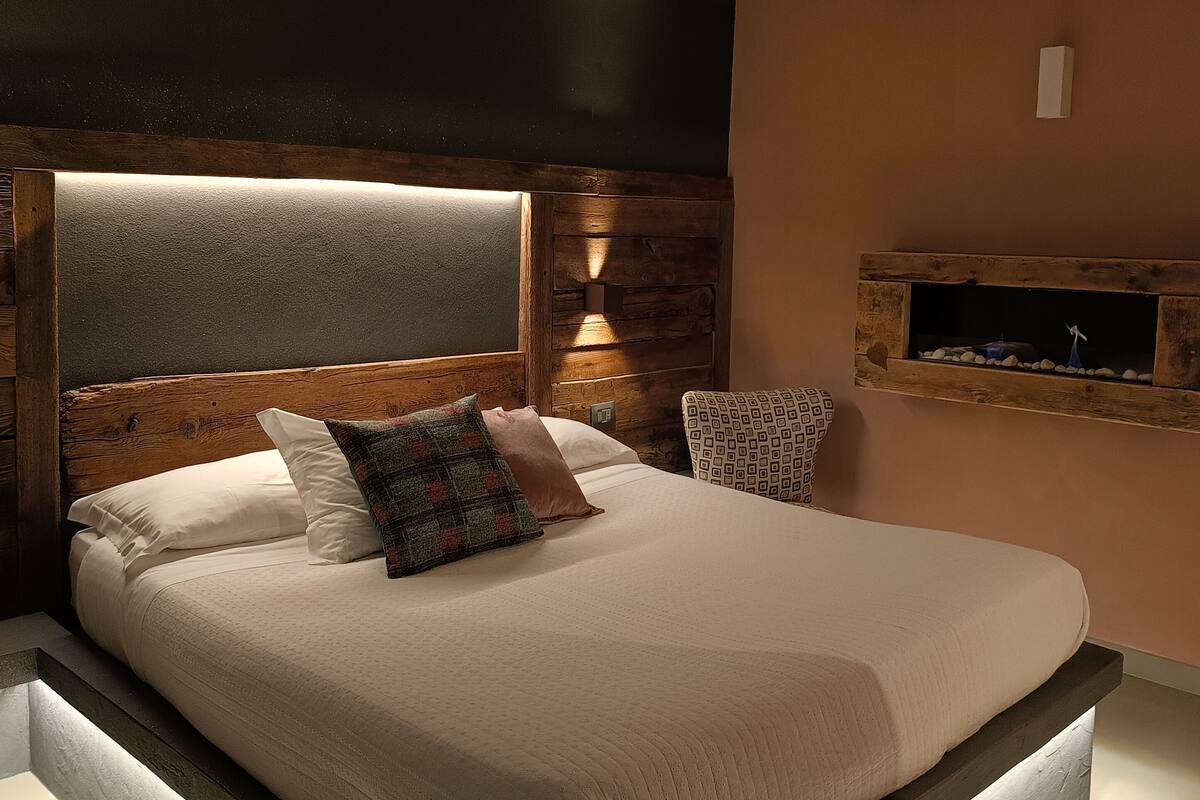 Une chambre à coucher moderne avec un grand lit, une tête de lit en bois et une étagère intégrée pour la télévision.