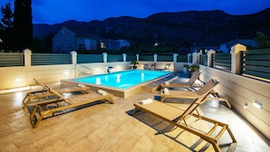 Una piscina al aire libre con sillones de descanso y vistas a montañas.