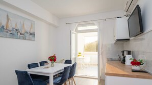 Una cocina moderna con comedor, un televisor montado en la pared y un cuadro con barcos a vela.