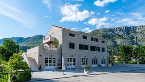 Un edificio de dos pisos con fachada de piedra, varias ventanas y techo plano.
