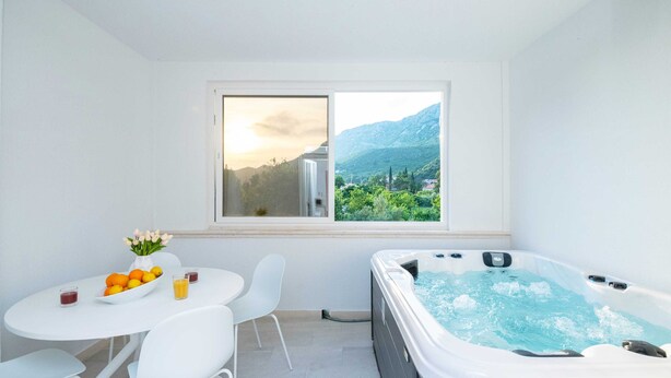 Un baño moderno con bañera de hidromasaje, una mesa con sillas y una ventana con vistas a la montaña.