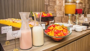 A buffet with labeled dishes including pork ham, yogurt, and a fruit salad.