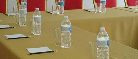 Una mesa de conferencias con botellas de agua, vasos y lápices.