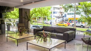 A modern lobby with a leather sofa, glass coffee tables, and potted plants.