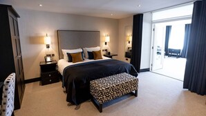 A modern hotel room with a large bed, bedside tables, a bench, and a view of the outdoors. - The Chester Hotel (Aberdeen)