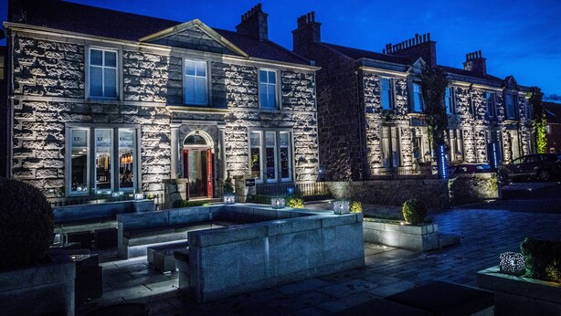 A stone building with a grand entrance, large windows, and a well-lit facade. - The Chester Hotel (Aberdeen)