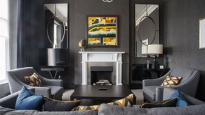 A modern living room with a fireplace, two armchairs, a coffee table, and a large abstract painting. - The Chester Hotel (Aberdeen)