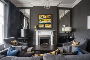 A modern living room with a fireplace, two armchairs, a coffee table, and a large abstract painting. - The Chester Hotel (Aberdeen)