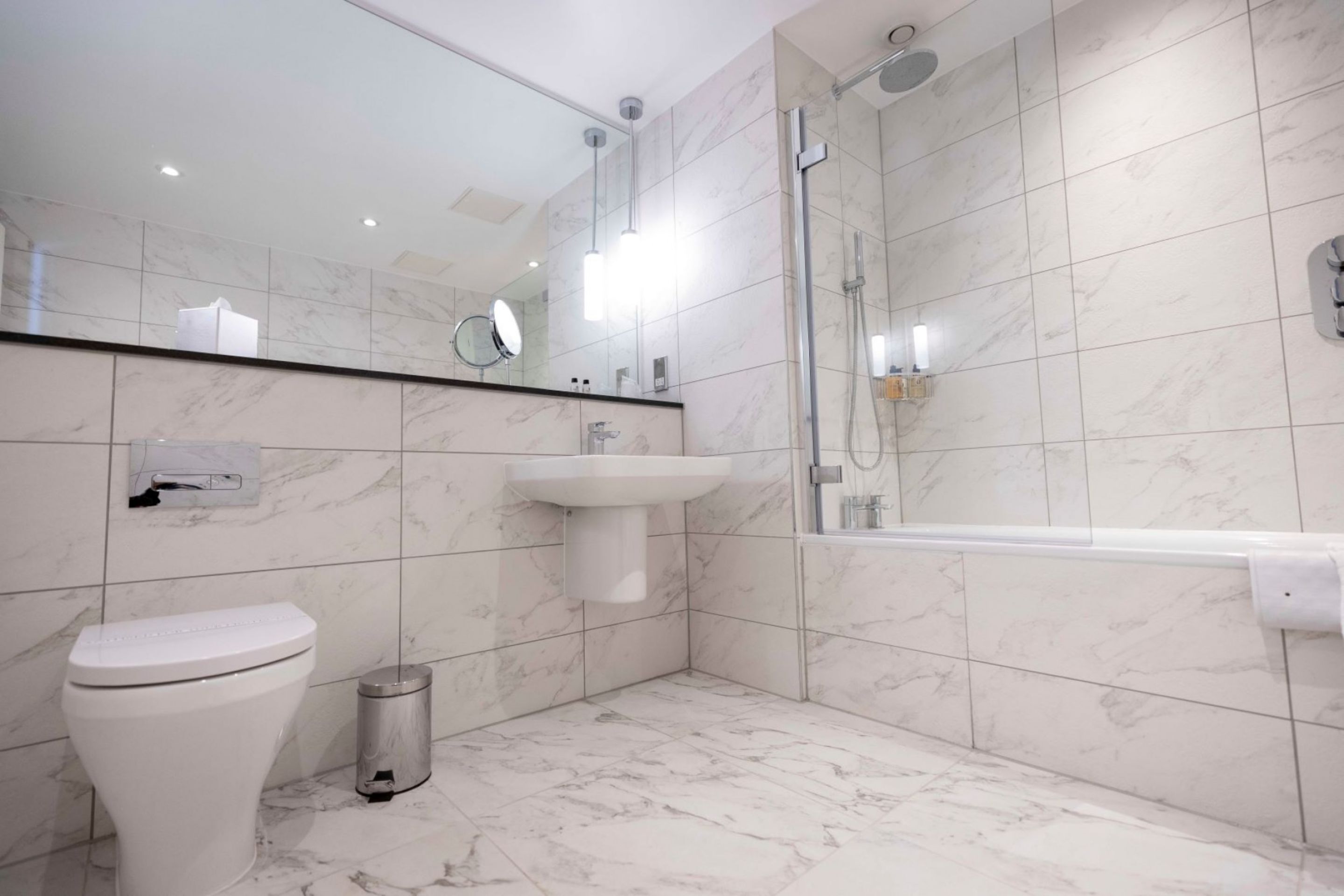 A modern bathroom with a toilet, sink, and shower.