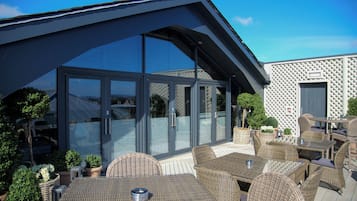 An outdoor patio with wicker furniture and a glass-enclosed dining area.