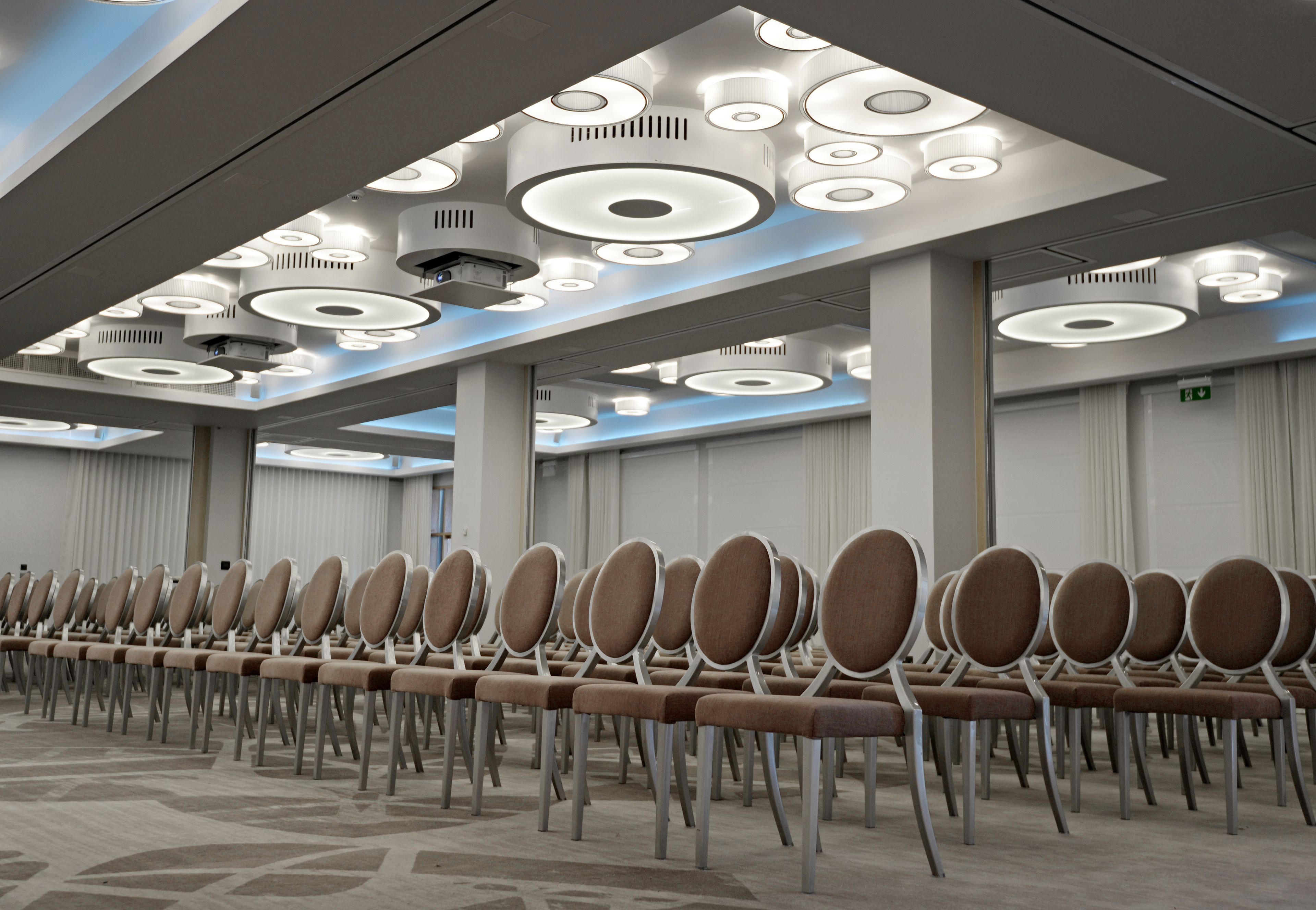 Un salón de conferencias con filas de sillas y un diseño moderno de techo.