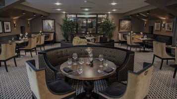 Un restaurant avec des tables rondes, des chaises et un sol à motifs.