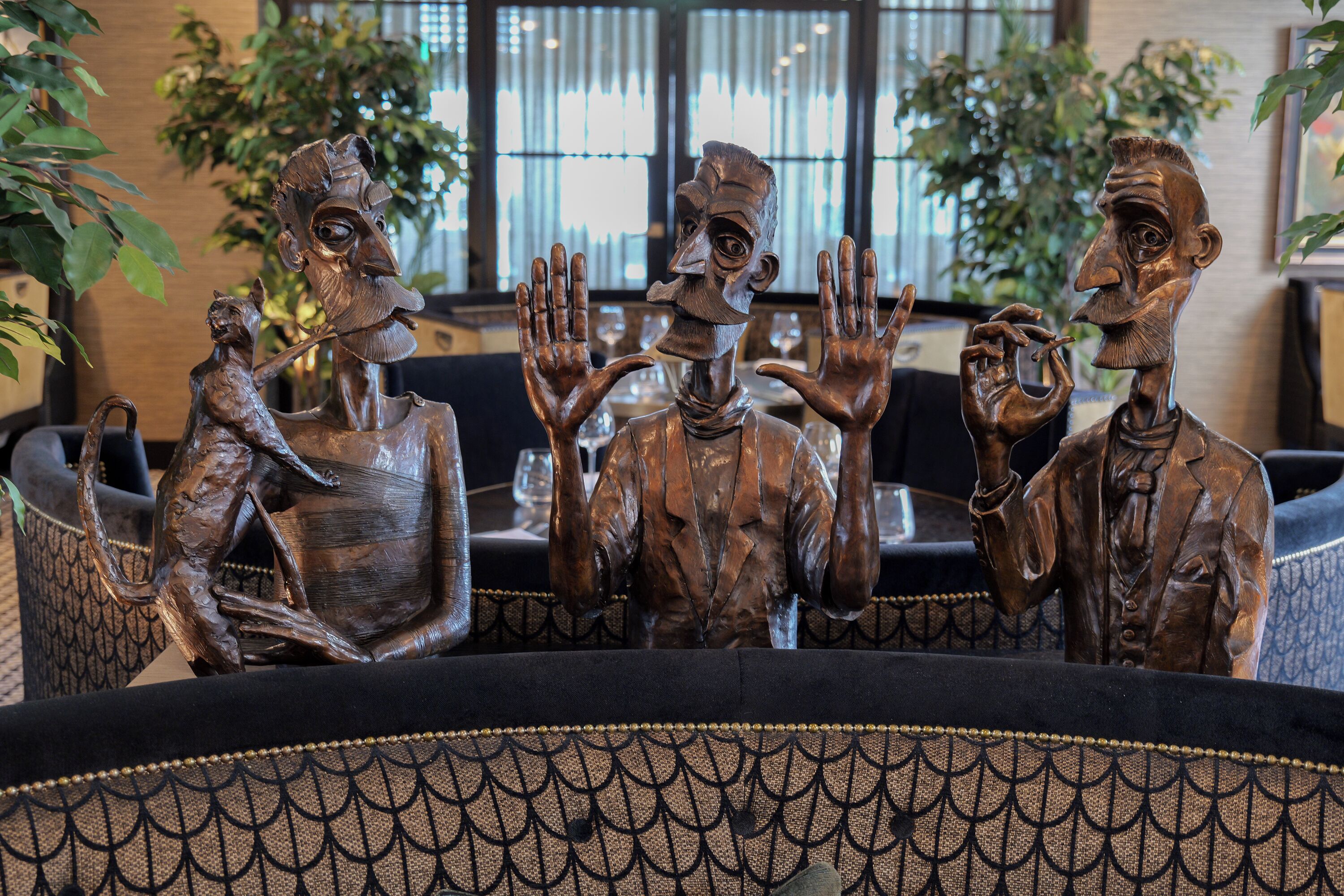 Una scultura raffigura tre figure sedute a un tavolo con tovaglia decorata.