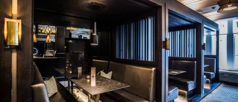 A modern bar area with leather seating, a marble table, and pendant lighting.