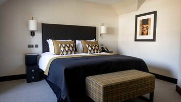 A hotel room with a large bed, a bedside table, a bench, and a framed picture on the wall.