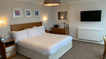 A bedroom with a large bed, bedside tables, a TV, and artwork on the wall.