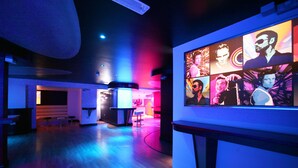 Um interior moderno com área de bar, piso de madeira e parede com vários retratos.