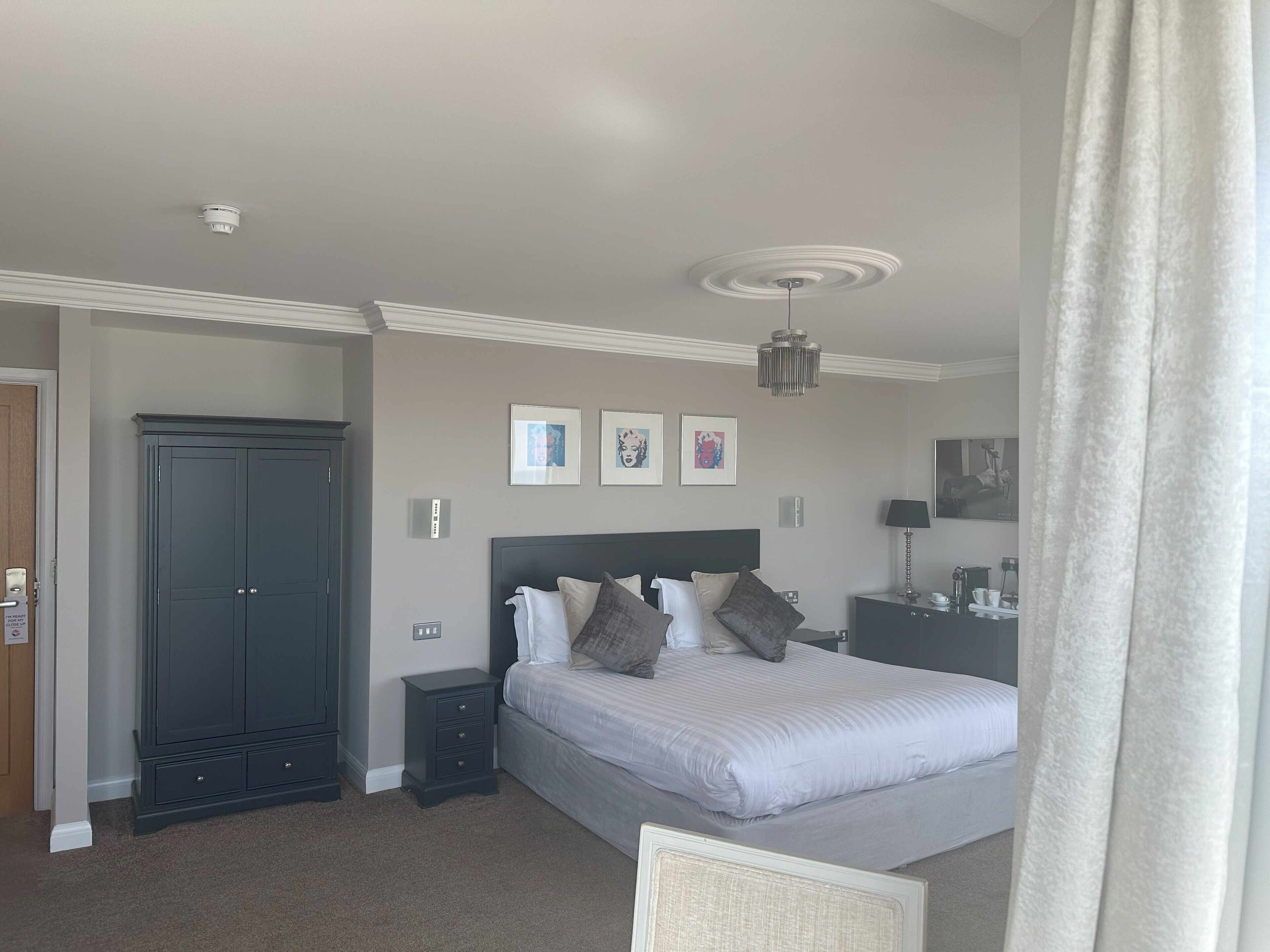 A bedroom with a bed, bedside tables, a wardrobe, and a ceiling light fixture.