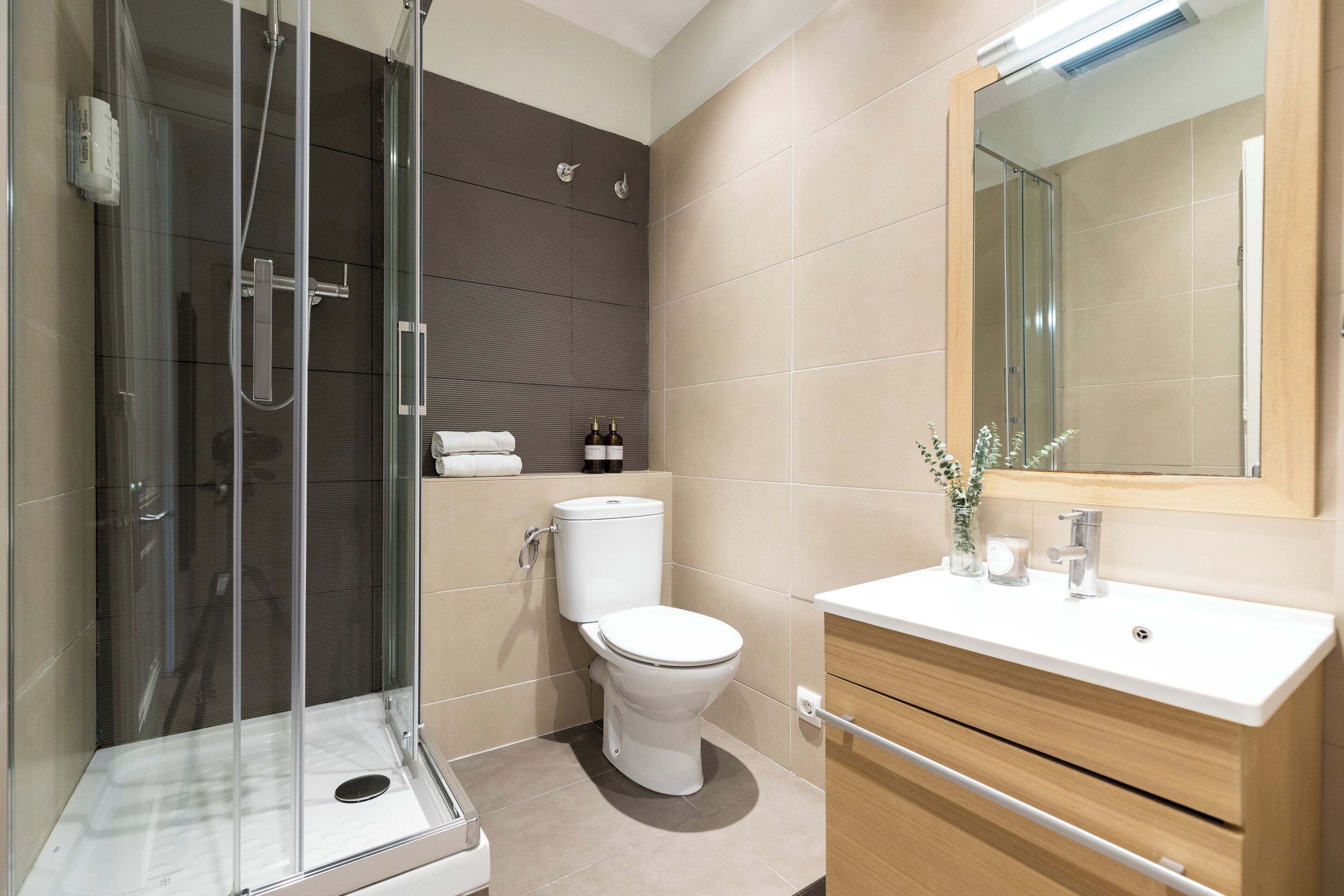 Une salle de bain moderne avec une douche à parois de verre, des toilettes et un meuble-lavabo avec un miroir.