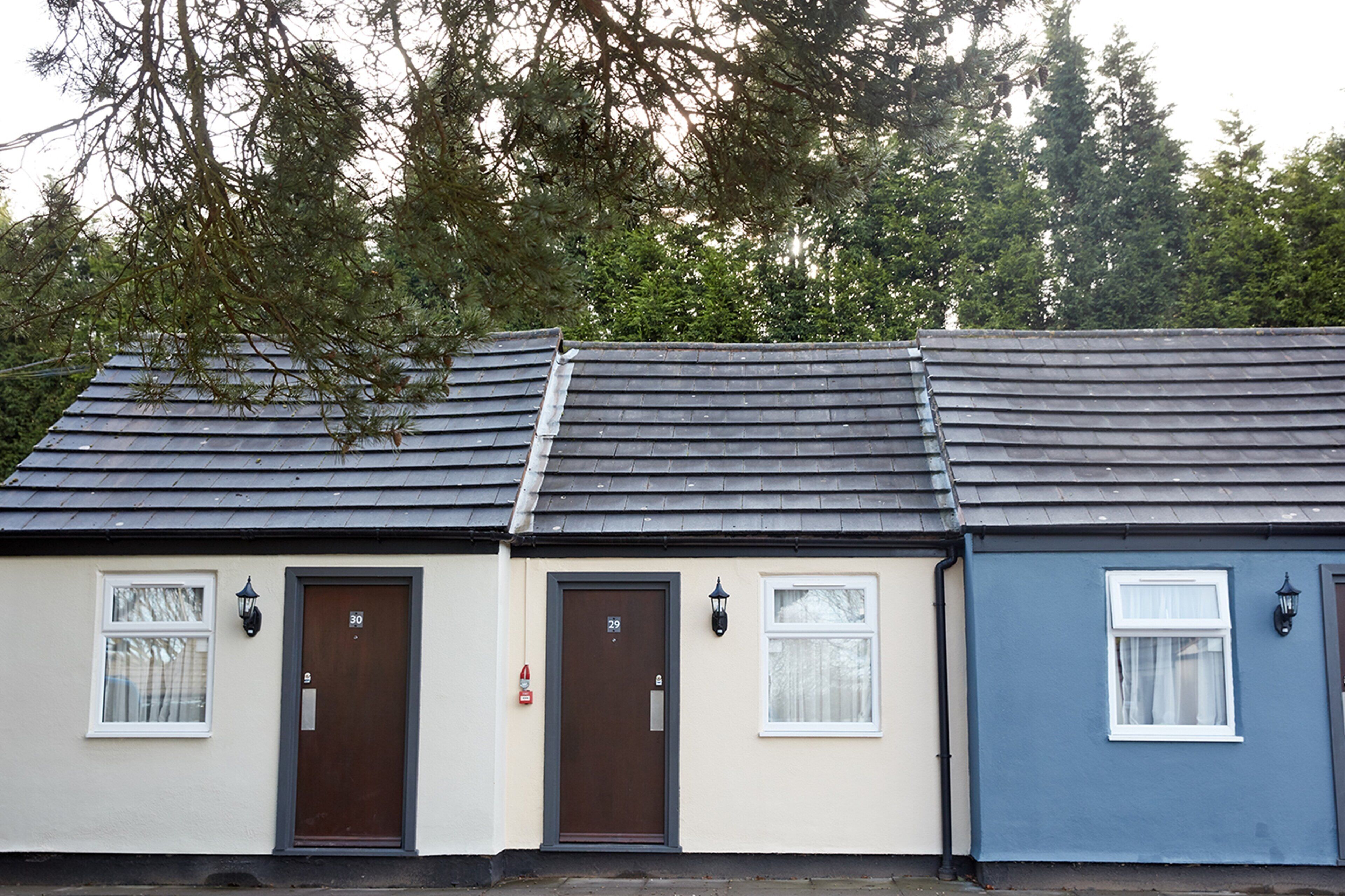 A row of three houses with distinct door numbers and different colored exteriors.