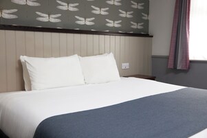 Una cama bien hecha con ropa blanca y una manta azul.