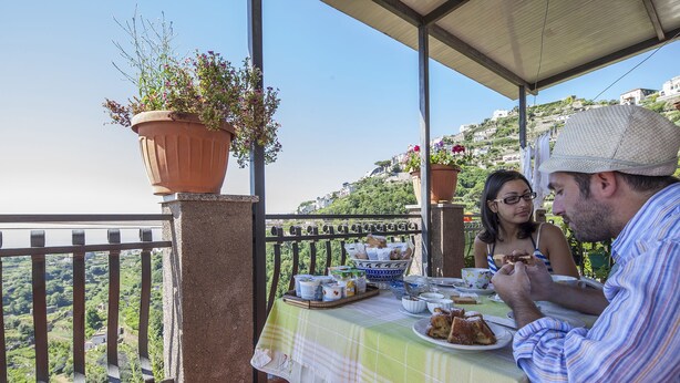 A balcony with a table set for two, overlooking a scenic hillside. - Il Rifugio del Poeta (Ravello)