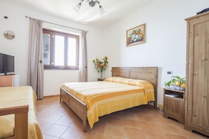 A bedroom with a wooden bed, a television, a window with curtains, a painting, and a cabinet. - Il Rifugio del Poeta (Ravello)