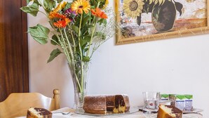 A dining table with a floral tablecloth, a vase of sunflowers, and a painting of sunflowers on the wall. - Il Rifugio del Poeta (Ravello)