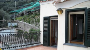 A residential building with a tiled balcony, a metal railing, and a door with green shutters. - Il Rifugio del Poeta (Ravello)