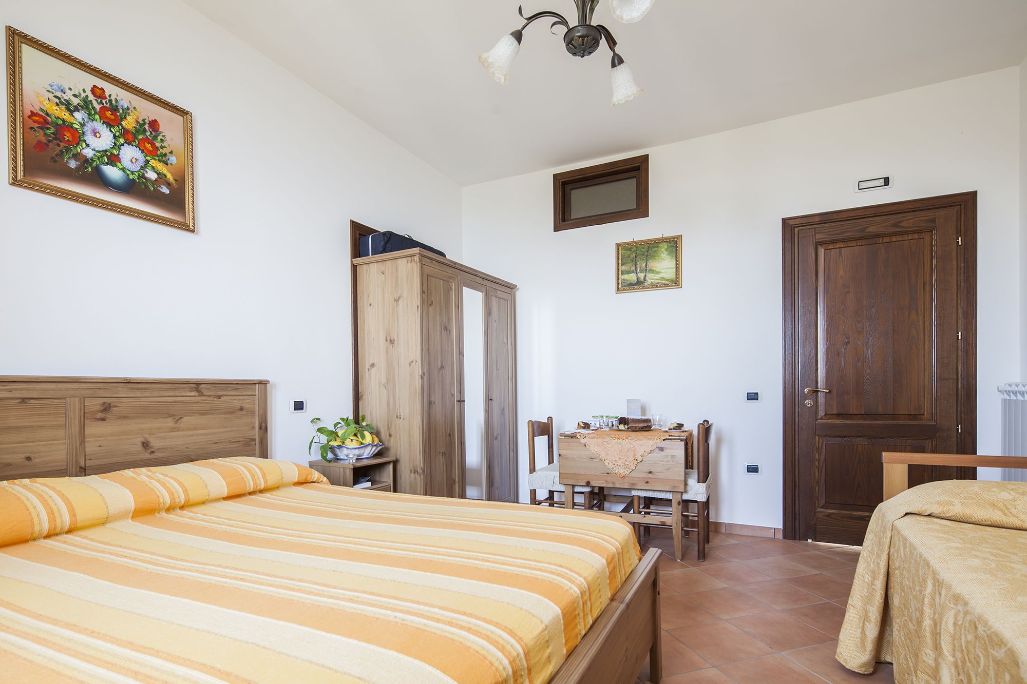 Un dormitorio con una cama, un armario de madera, un escritorio con una silla y una puerta.