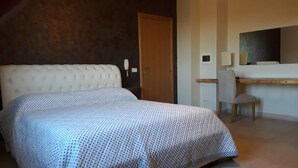 Una habitación de hotel con una cama grande, un escritorio con una silla, un teléfono y un espejo.