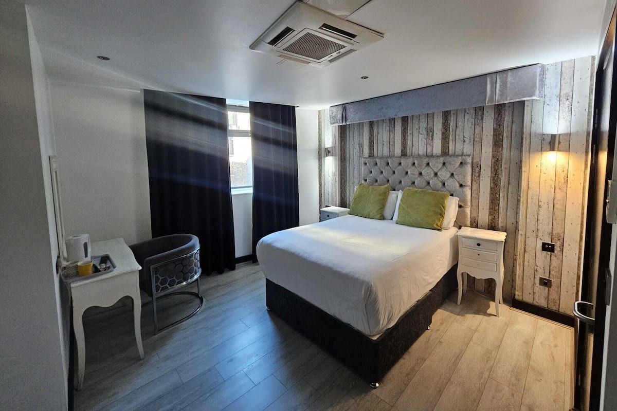 Hotellihuone, jossa on sänky, yöpöydät, työpöytä ja tuoli.